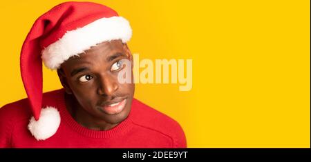 Interessantes Angebot. Neugierig African Guy In Santa Hat Overhear Auf Gelben Hintergrund Stockfoto