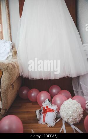 Eine vertikale Aufnahme des Brautkleides, das an der Tür hängt, über rosa Ballons Stockfoto