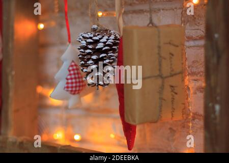 Eine Girlande aus Weihnachtsschmuck, ein kleines Geschenk, Tannenzapfen, Weihnachtsbaum, hängen an einem Seil mit glühenden Girlanden Stockfoto