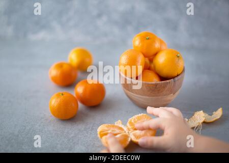 Reife Clementinen Früchte auf grauem Tisch in minimalem Stil. Gesunde Ernährung und saubere Ernährung Konzept. Selektiver Fokus. Speicherplatz kopieren. Stockfoto