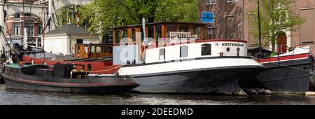 AMSTERDAM, NIEDERLANDE - 01. MAI 2018: Panoramablick auf Boote, die auf einem Kanal festgemacht sind Stockfoto