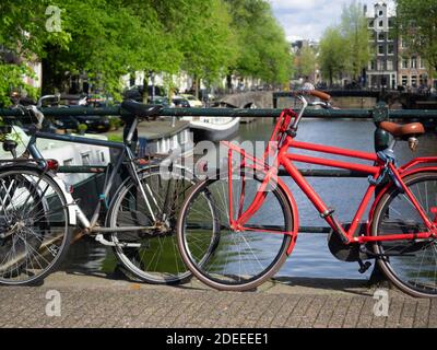 AMSTERDAM, NIEDERLANDE - 01. MAI 2018: Geparkte Fahrräder auf einer Brücke über die Brouwersgracht mit Blick auf den Kanal im Hintergrund Stockfoto
