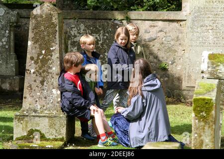 Auld Kirk , Alloway, Ayrshire, Schottland, Großbritannien. 24 Mai 2014. Ein Geschichtenerzähler auf dem Friedhof, der Kinder erzählt, die die Geschichte der Gräber des Dichters Robert Burns erzählen Stockfoto