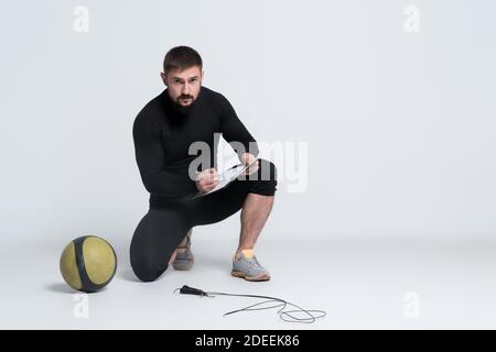 Personal Fitness Trainer Hold Clipboard mit Trainingsplan auf weiß Hintergrund Stockfoto
