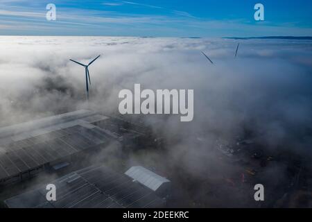 Windturbine, die über starkem Nebel sitzt, Nebel bei einem frühen Sonnenaufgang in südwales großbritannien. Windpark erzeugt grüne Energie Stockfoto