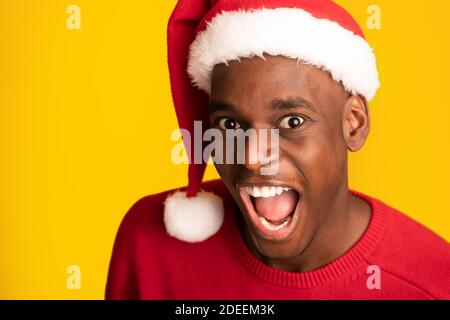 Nahaufnahme Von Crazy Emotional Black Guy In Santa Hat Über Gelber Hintergrund Stockfoto