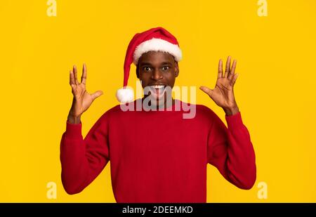 Weihnachtsangebot. Schockiert Black Man In Santa Hat Heben Hände In Aufregung Stockfoto