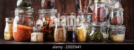 Speisenangebot. Rohes Getreide, Nudeln, Grütze, Bio-Hülsenfrüchte und nützliche Samen in Gläsern. Vegane Quelle von Protein und Energieressourcen. Rustikale Holzkitk Stockfoto