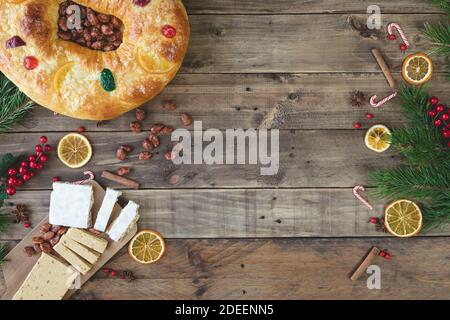 Roscón de Reyes und Nougat auf einem Holzsockel mit Weihnachtsschmuck. Drei Könige Kuchen und Nougat. Typisches Essen. Speicherplatz kopieren. Stockfoto