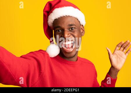 Festliches Selfie. Fröhlicher Schwarzer Kerl In Santa Hat Selbstporträt Nehmen, Weihnachten Feiern Stockfoto