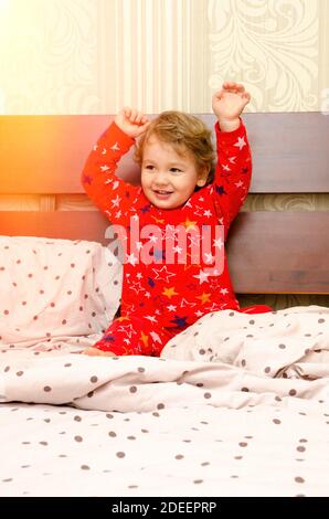 Kleiner Junge im Schlafanzug auf dem Bett Stockfoto