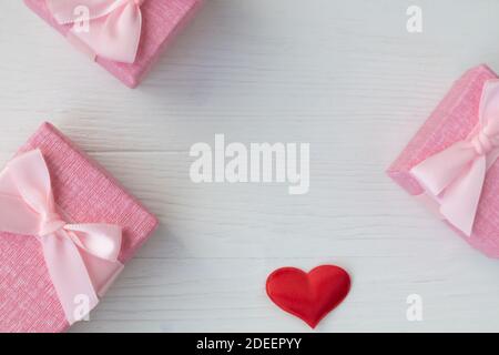 Schachteln für kleine Geschenke in Pastellfarben und roten Satinherzen auf hellem Hintergrund mit Platz für Text. Werbung. Stockfoto
