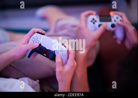 Verschiedene Generationen von PlayStation-Konsolen-Controllern: PS5 DualSense-Controller und PS4 DualShock-Controller in den Händen von Spielern. Moskau - Stockfoto