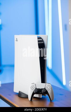 Die neue Sony Spielekonsole PlayStation 5 und der DualSense Controller in blauem Neonlicht. Moskau - November 28 2020. Stockfoto