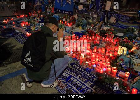 Ein Napoli-Fan zündet eine Kerze an, vor den Toren des Stadions, in Erinnerung an Diego Armando Maradona , in den Tagen nach dem Tod Stockfoto