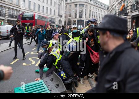 Anti-Lockdown Protest, London, 28. November 2020. Polizeibeamte greifen einen Protestierenden über eine Barriere auf die Straße in der Regent Street an. Stockfoto