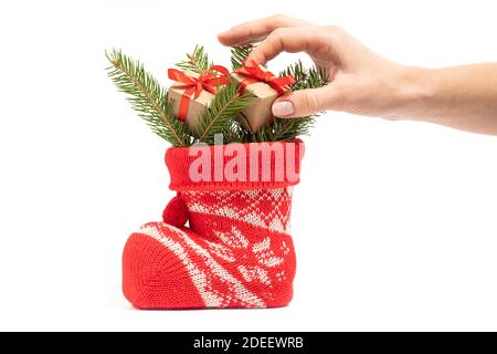 Weibliche Hand legt kleine Geschenke mit Tannenzweigen in Santa's Boot. Hohe Qualität Stockfoto