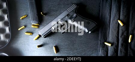 Draufsicht der Handfeuerwaffe auf schwarzem Hintergrund mit Kugeln um. 9mm Pistole mit Munition auf dunklem Tisch. Stockfoto