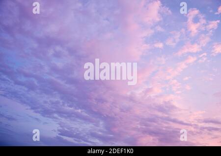 Schöner blauer Himmel Hintergrund. Weiche weiße Wolken bei Sonnenuntergang. Viele rosa, magenta und orange Töne und Muster von Wolken. Stockfoto