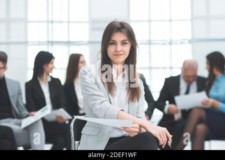 Junge Geschäftsfrau vor dem Hintergrund ihrer Kollegen. Stockfoto