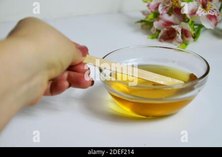 Bild von flüssigem Zucker für Haare Enthaarung Wachs Glas aus goldenem Honig Closep mit Frangipani Blumen. Vorbereitung natürliche Schönheit Körper behandeln Stockfoto