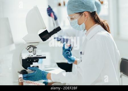 Wissenschaftlerin sitzt vor einem Mikroskop. Stockfoto