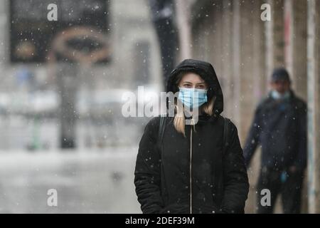 Bukarest, Rumänien - 30. November 2020: Menschen mit Schutzmasken wandern während des Coronavirus-Ausbruchs durch den Schnee. Stockfoto