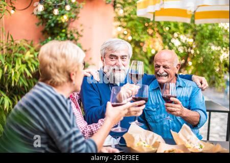 Ältere Leute toasten Wein in der Restaurant Bar - Neu normal Freundschaftskonzept mit glücklichen reifen Freunden, die Spaß zusammen haben Pub im Freien im Frühling Stockfoto