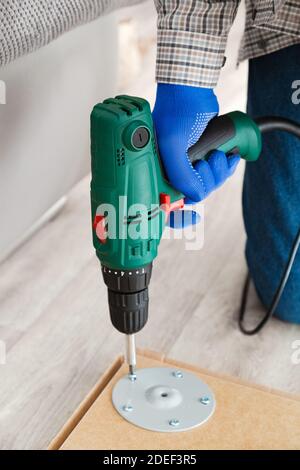 Möbelmontage Prozess, Master sammelt Tischmöbel mit Bohrwerkzeug Instrument. Der elektrische Bohrer arbeitet in Handarbeit zu Hause. Umzug, nach Hause Stockfoto