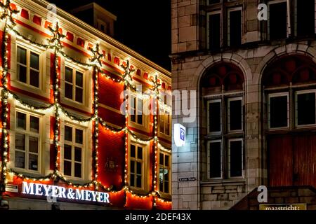 Maastricht, NIEDERLANDE - 25. Dezember 2019 Urban Christmas Fassadendekorationen. Weihnachten Girlande leuchtet auf Fensterhaus. Festliche Beleuchtung der Stadt Stockfoto