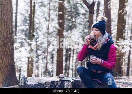 Ein Tourist auf einer Wanderung im Herbstwald auf einem Bergweg ruht, essen und trinken heißen Tee. Stockfoto