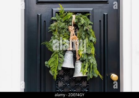 Weihnachtskranz mit Glocken am Eingang vintage schwarze Tür draußen. Veranda Eingangstür dekoriert mit festlichen Weihnachtskranz Dekor. Traditionell Stockfoto