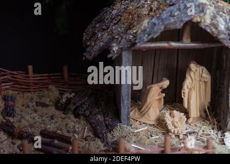 Weihnachtskrippe, Maria, Josef und Jesuskind, geschnitzte Holzfiguren in rustikalem Holzstall, Kopierraum, Hintergrund Stockfoto