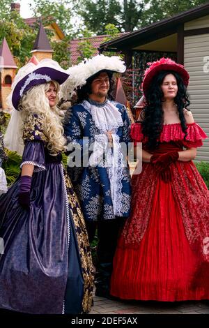 Zwei junge Damen in luxuriösen Vintage-Kleidern mit einem Mann, auch in Vintage-Kleidung.Puppentheater Museum, Juli 2020 in Preili, Lettland. Stockfoto