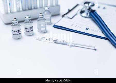 Covid 19-Impfstoff und medizinisches Gesundheitskonzept. Impfstoffe Fläschchen und Spritze auf weißem Arzt oder Wissenschaftler Tabelle. Stockfoto