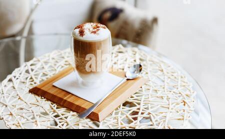 Heißer Latte oder Cappuccino Kaffee auf dem Tisch im Cafe oder Küche in der Nähe des Fensters mit Kopierraum.Morning Kaffee Latte mit Milch und Schokolade oben drauf Stockfoto