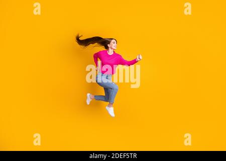 In voller Länge Profil Foto von schönen Dame springen Luft lang Frisur tragen rosa Pullover Jeans Sneakers isoliert gelbe Farbe Hintergrund Stockfoto