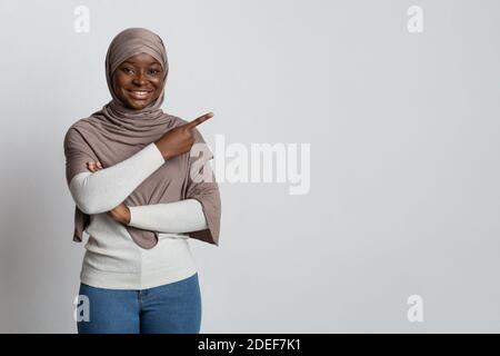 Aktivieren Sie Diese Option. Lächelnde Afrikanische Muslimische Lady Zeigt Auf Copy Space Mit Finger Stockfoto