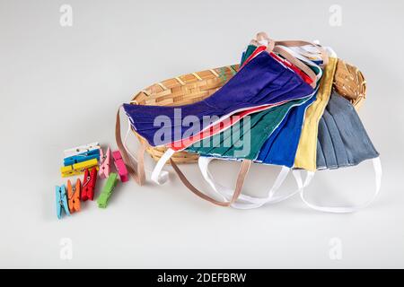 Drei gefaltete Gesichtsmasken mit elastischen Ohrschlaufen - gestapelt, weiße Maske oben, blau und schwarz im Hintergrund. Wiederverwendbare waschbare Masken aus Baumwollgewebe in h Stockfoto