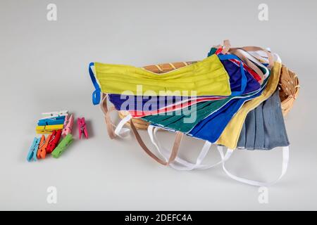Drei gefaltete Gesichtsmasken mit elastischen Ohrschlaufen - gestapelt, weiße Maske oben, blau und schwarz im Hintergrund. Wiederverwendbare waschbare Masken aus Baumwollgewebe in h Stockfoto