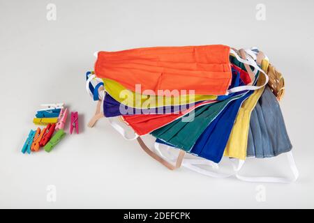 Drei gefaltete Gesichtsmasken mit elastischen Ohrschlaufen - gestapelt, weiße Maske oben, blau und schwarz im Hintergrund. Wiederverwendbare waschbare Masken aus Baumwollgewebe in h Stockfoto