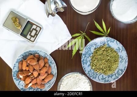 Kochen mit Marihuana: Tisch mit Cannabis und verschiedenen Zutaten, um ein Rezept mit Marihuana zu kochen. Stockfoto