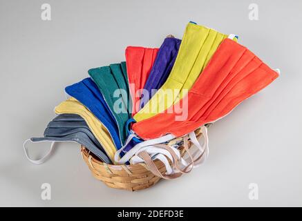 Drei gefaltete Gesichtsmasken mit elastischen Ohrschlaufen - gestapelt, weiße Maske oben, blau und schwarz im Hintergrund. Wiederverwendbare waschbare Masken aus Baumwollgewebe in h Stockfoto