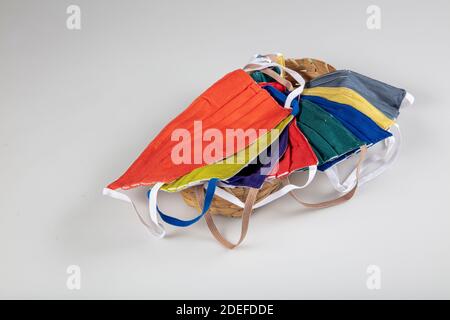 Drei gefaltete Gesichtsmasken mit elastischen Ohrschlaufen - gestapelt, weiße Maske oben, blau und schwarz im Hintergrund. Wiederverwendbare waschbare Masken aus Baumwollgewebe in h Stockfoto