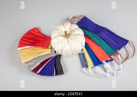 Drei gefaltete Gesichtsmasken mit elastischen Ohrschlaufen - gestapelt, weiße Maske oben, blau und schwarz im Hintergrund. Wiederverwendbare waschbare Masken aus Baumwollgewebe in h Stockfoto