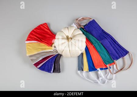 Drei gefaltete Gesichtsmasken mit elastischen Ohrschlaufen - gestapelt, weiße Maske oben, blau und schwarz im Hintergrund. Wiederverwendbare waschbare Masken aus Baumwollgewebe in h Stockfoto
