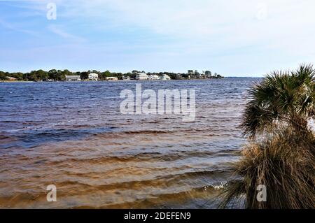 Eine schöne Aussicht auf das Festland von der gegenüberliegenden Küste des Golfs von Mexiko, von Santa Rose Island, das blaue Wasser des Ozeans glänzen mit dem bräunlichen Stockfoto