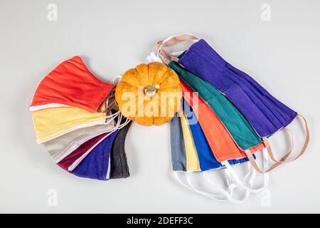 Drei gefaltete Gesichtsmasken mit elastischen Ohrschlaufen - gestapelt, weiße Maske oben, blau und schwarz im Hintergrund. Wiederverwendbare waschbare Masken aus Baumwollgewebe in h Stockfoto