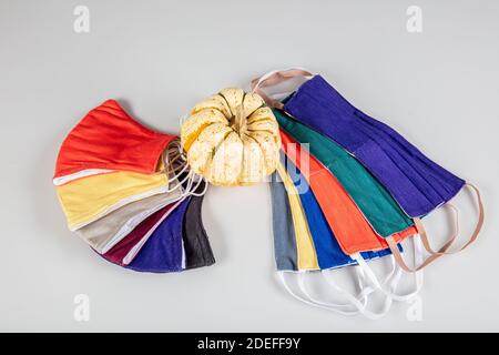 Drei gefaltete Gesichtsmasken mit elastischen Ohrschlaufen - gestapelt, weiße Maske oben, blau und schwarz im Hintergrund. Wiederverwendbare waschbare Masken aus Baumwollgewebe in h Stockfoto