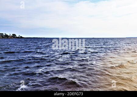 Eine schöne Aussicht auf das Festland von der gegenüberliegenden Küste des Golfs von Mexiko, von Santa Rose Island, das blaue Wasser des Ozeans glänzen mit dem bräunlichen Stockfoto